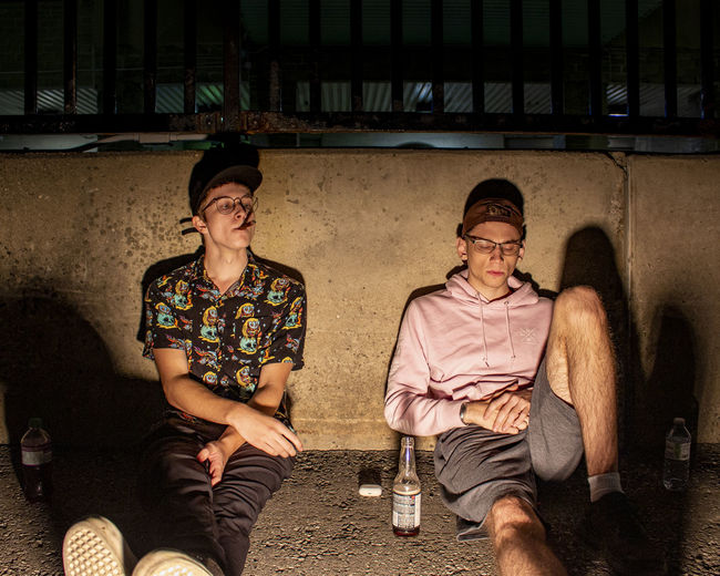 Full length view of young men drinking sitting outdoors