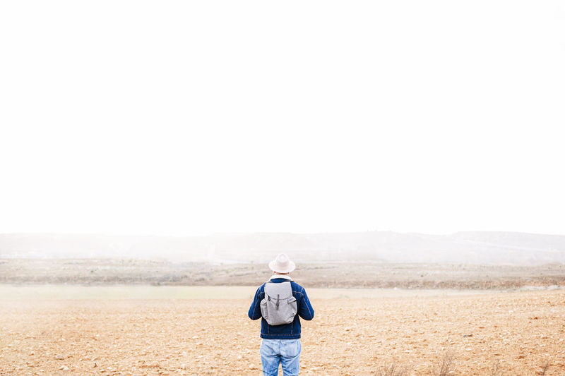 Man with back pack standing in front of sky