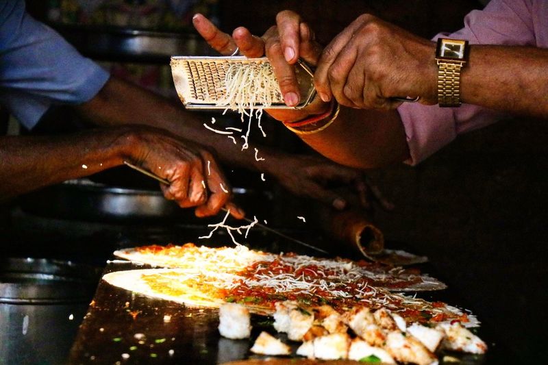 Cropped hands of man grating cheese on street food