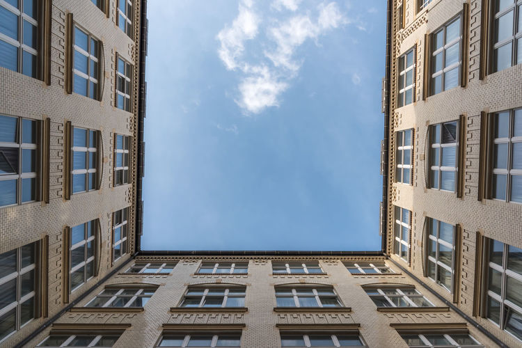 A look up at a white cloud from a courtyard of an old building