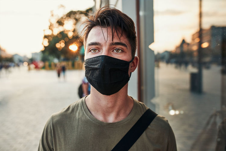 Portrait of young man wearing mask standing in city