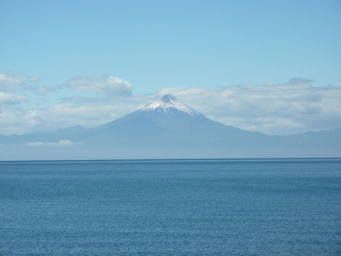 Scenic view of sea and mountains against blue sky