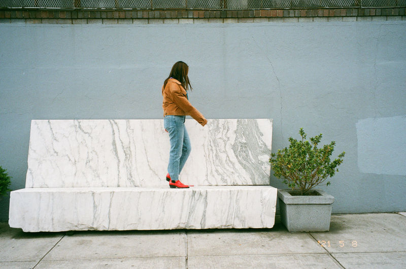 Woman on marble bench against wall