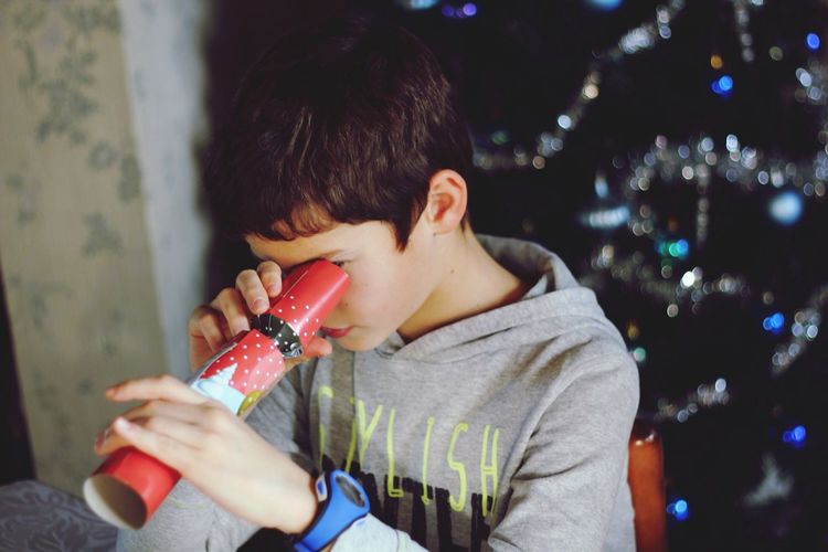 Close-up of boy looking through toy at night during christmas