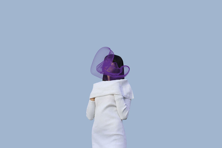 Woman with purple scarf standing against gray background
