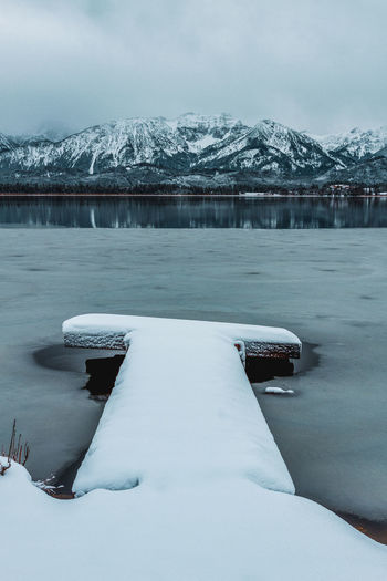 The hopfensee with the allgäu alps in winter. germany. in the foreground snow-covered jetty.