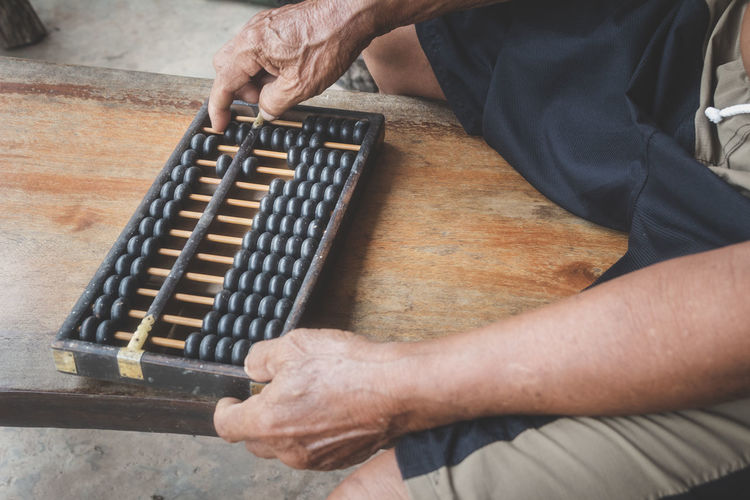 Midsection of man playing with abacus