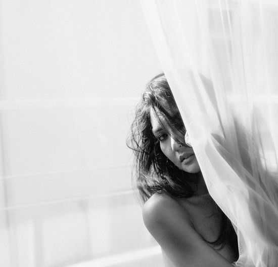 Portrait of seductive woman by curtain at home