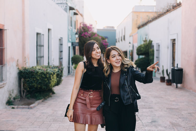 Happy women standing on street in city