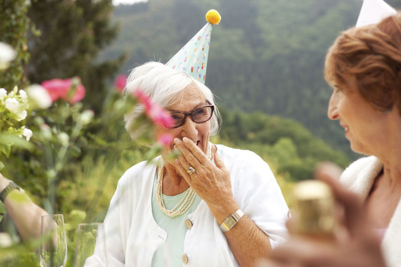 Senior ladies laughing at celebration, wearing party hats