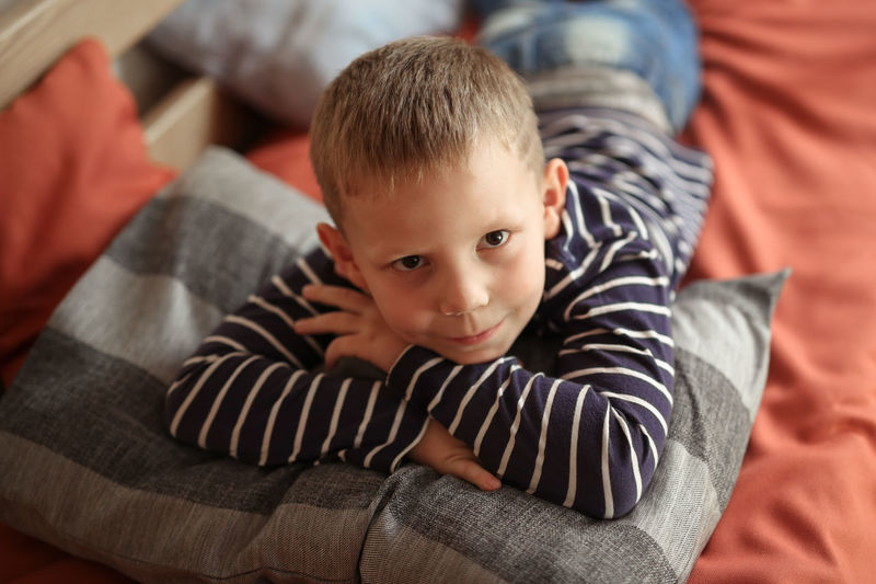 Thoughtful serious offended boy hugs a pillow on the couch, concept children's problems  loneliness.