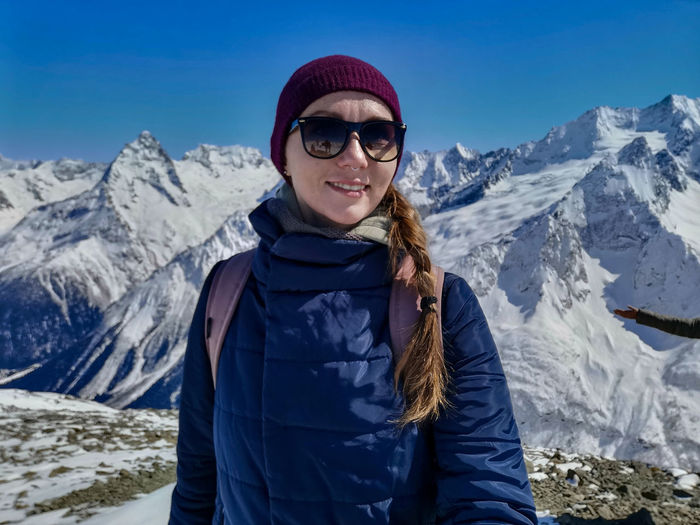 Portrait of woman standing on snowcapped mountains during winter