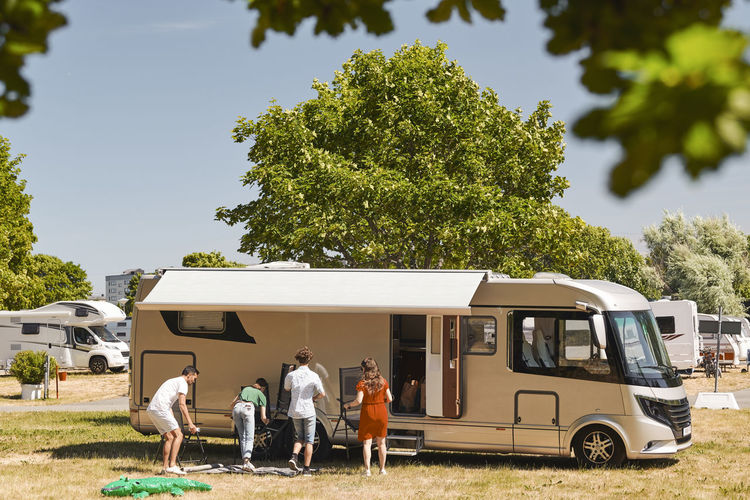 Family against motor home camping at trailer park during summer vacation