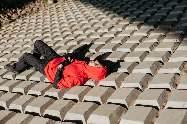 Young man in red hoodie. lying under the sun. unusual texture.
