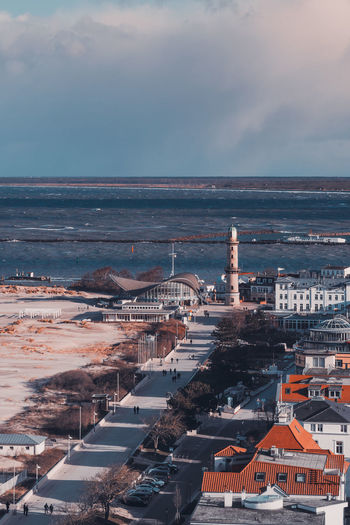 High angle view of buildings by sea against cloudy sky during sunset