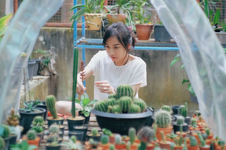 WOMAN HOLDING POTTED PLANT