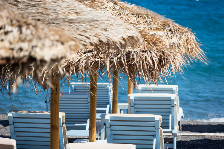 Empty chairs on beach against blue sea