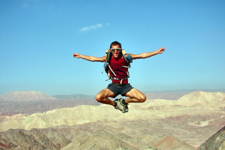 Full length of man jumping over landscape against sky