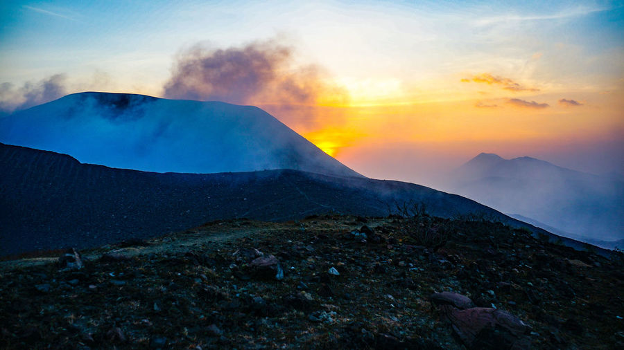 Scenic view of volcanic mountain against sky during sunset