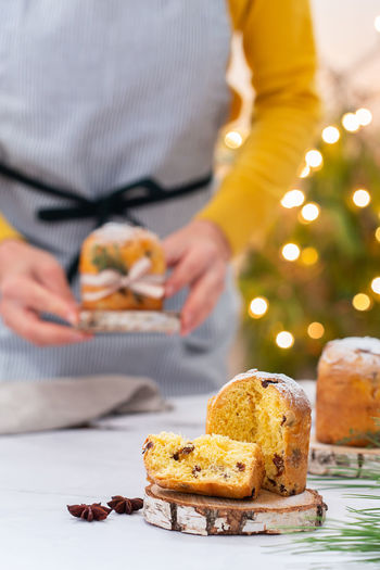 Traditional italian christmas cake panettone on a rustic table. female hands are holding cake