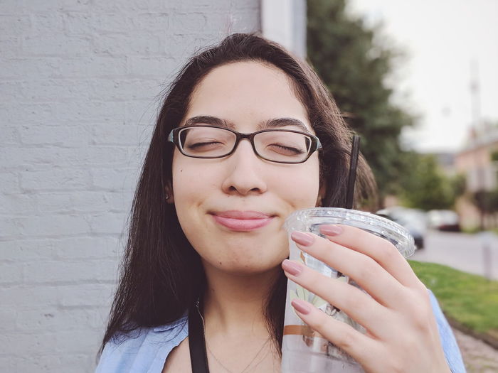 Smiling young woman holding drink outdoors