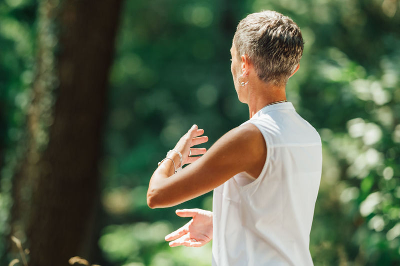Middle aged woman practicing tai chi chuan in the park. close up on hands position