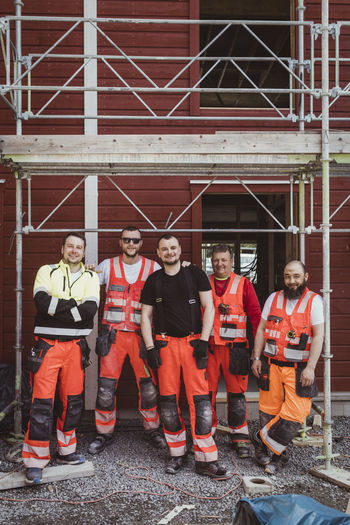Full length of male construction workers standing together at site