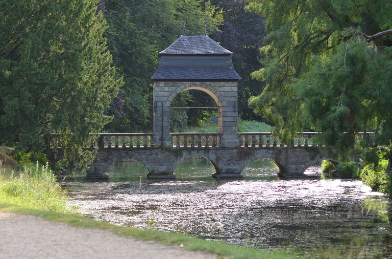 Arch bridge over lake against trees