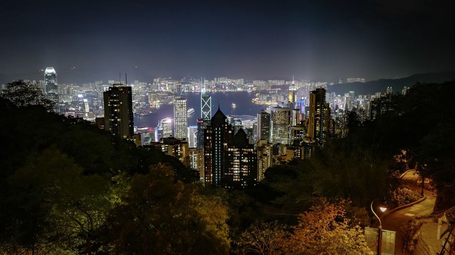 High angle view of illuminated city by victoria harbour at night