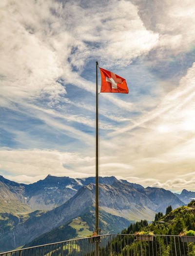 Swiss flag against mountain range against sky