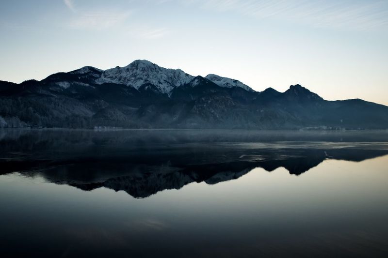 Reflection of mountains in lake against sky during winter