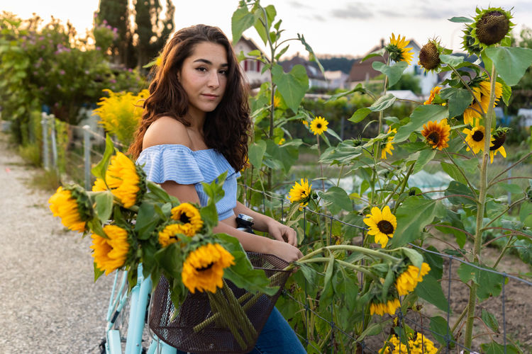 Portrait of young woman with sunflower in garden