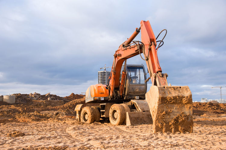 Bucked wheel excavator digs ground at a construction site for installing concrete storm pipes.