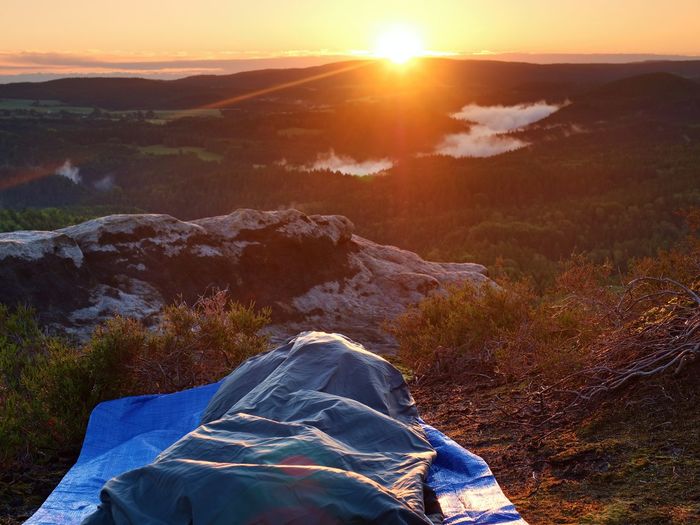 Beautiful awakening in sleeping bag on a rock ledge. birds are singing in forest with clouds of mist
