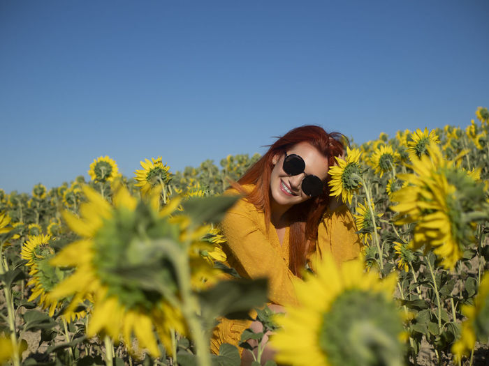 Portrait of woman standing amidst yellow flowering plant against sky