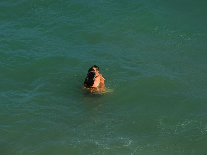 High angle view of romantic couple embracing in sea