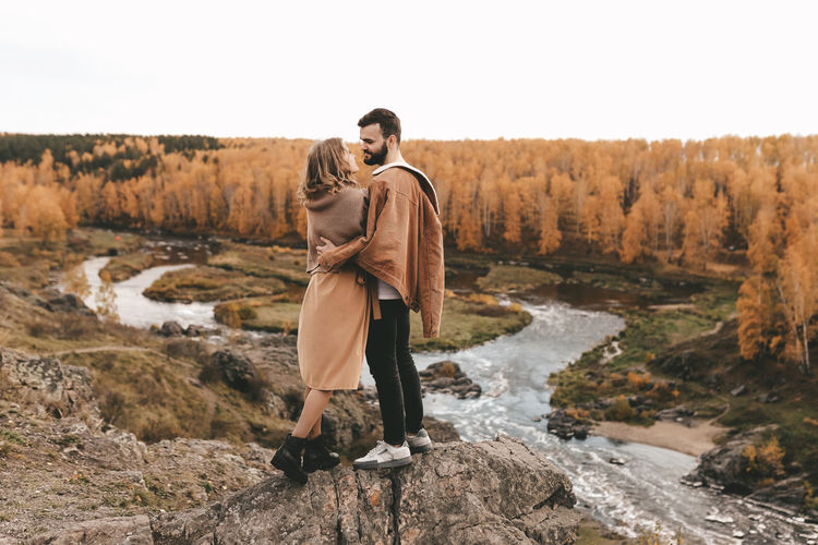 A happy couple in love a man and a woman are traveling walking hiking in the autumn forest in nature