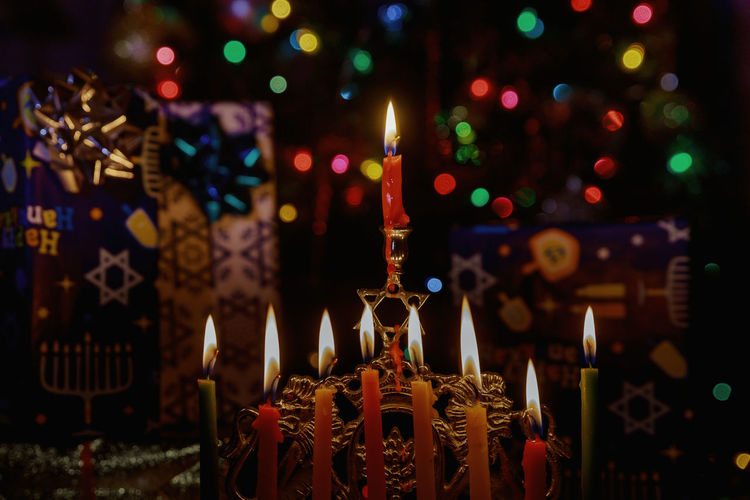 Close-up of illuminated candles against lighting equipment