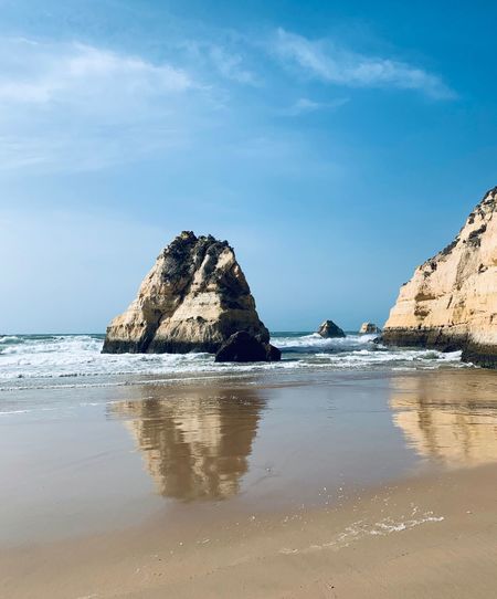 Rock formation on beach against sky