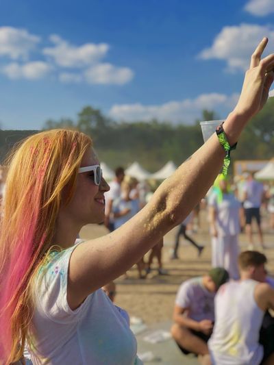 Young woman wearing sunglasses with arm raised in music festival