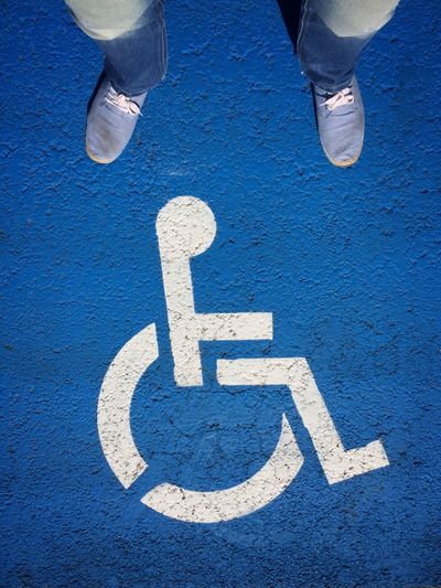Low section of man standing on disabled sign