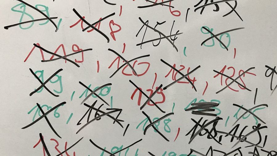 Close-up of numbers with cross shapes on whiteboard
