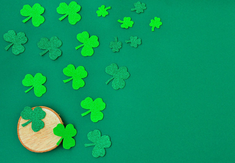 Saint patricks day background with green shamrock laid out next to a wooden saw, a place for text.