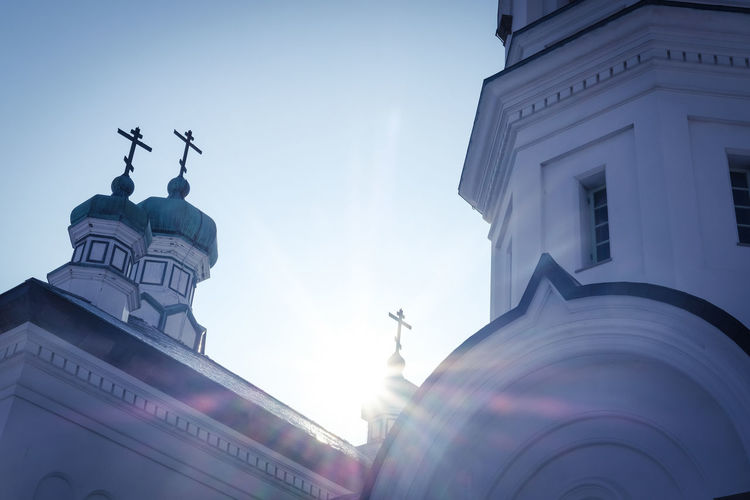 Low angle view of cross amidst buildings against sky