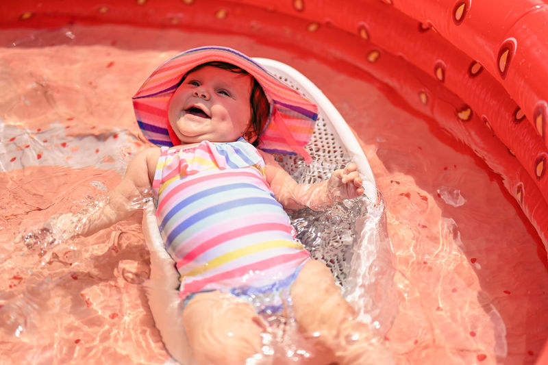 Full length of a baby girl smiling in a kiddie pool