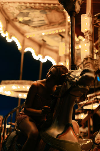 Millennial woman riding carousel horse