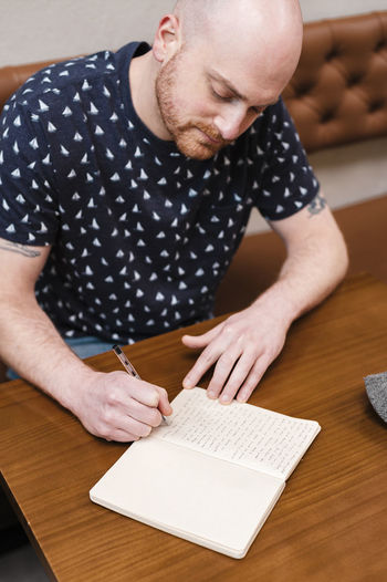 Midsection of man reading book on table