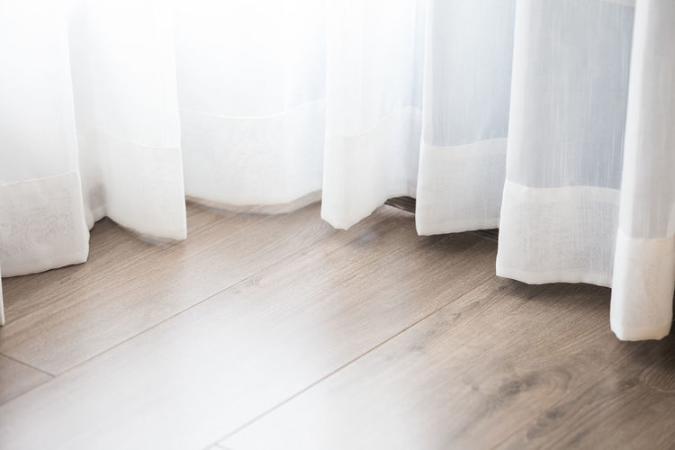 Close-up of white curtain over hardwood floor