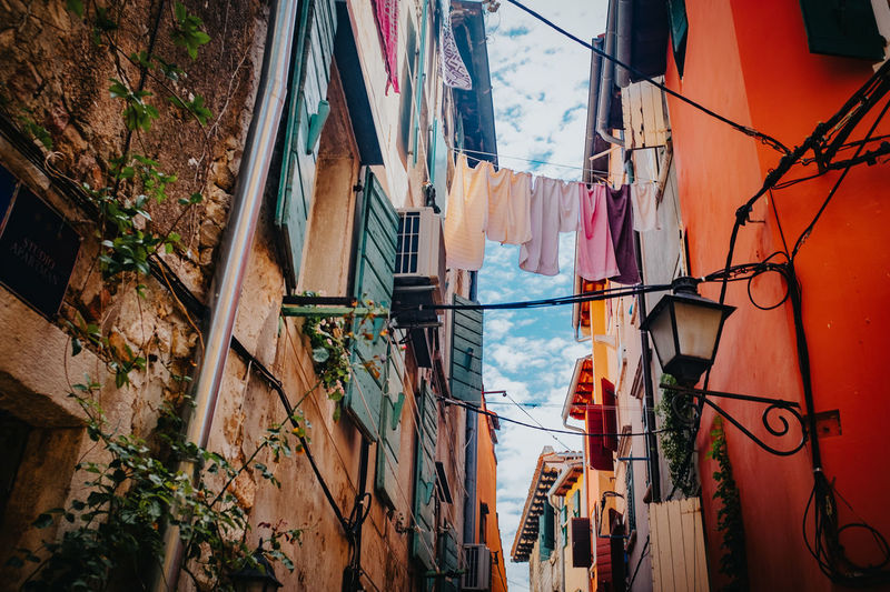 Low angle view of clothes hanging in alley amidst buildings