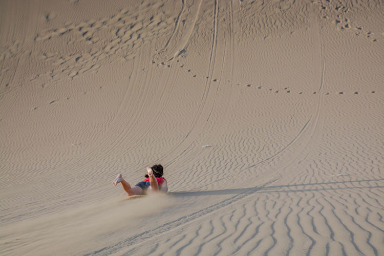 Rear view of woman sandboarding in desert